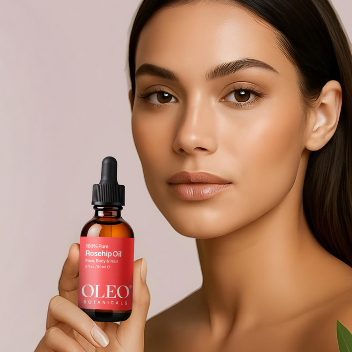 Woman holding a bottle of OLEO Botanicals Rosehip Oil against a pink background